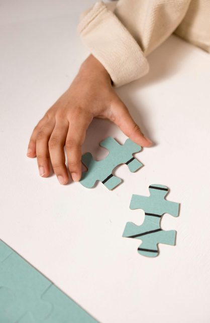 A child's hand in focus, solving a pastel blue puzzle, illustrating focus and learning.